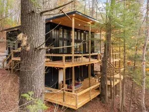 Modern container home with multi-level decks nestled in a wooded landscape.